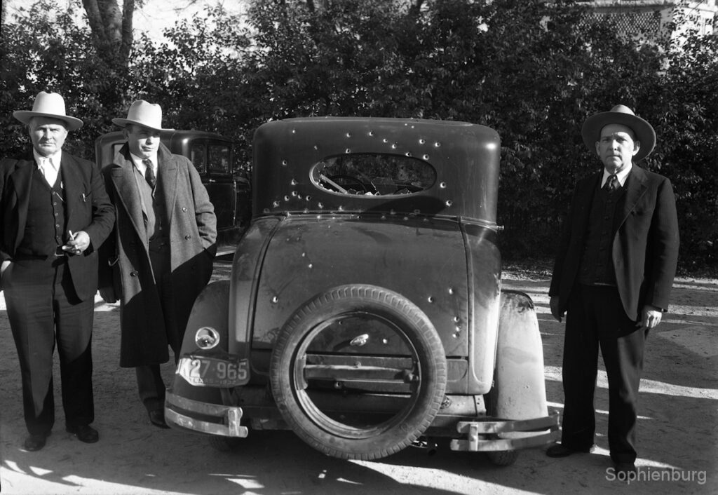 Sheriff August Knetsch, Deputy Ed Schleyer, and Charles Marion with bullet-riddled getaway car, 1933.