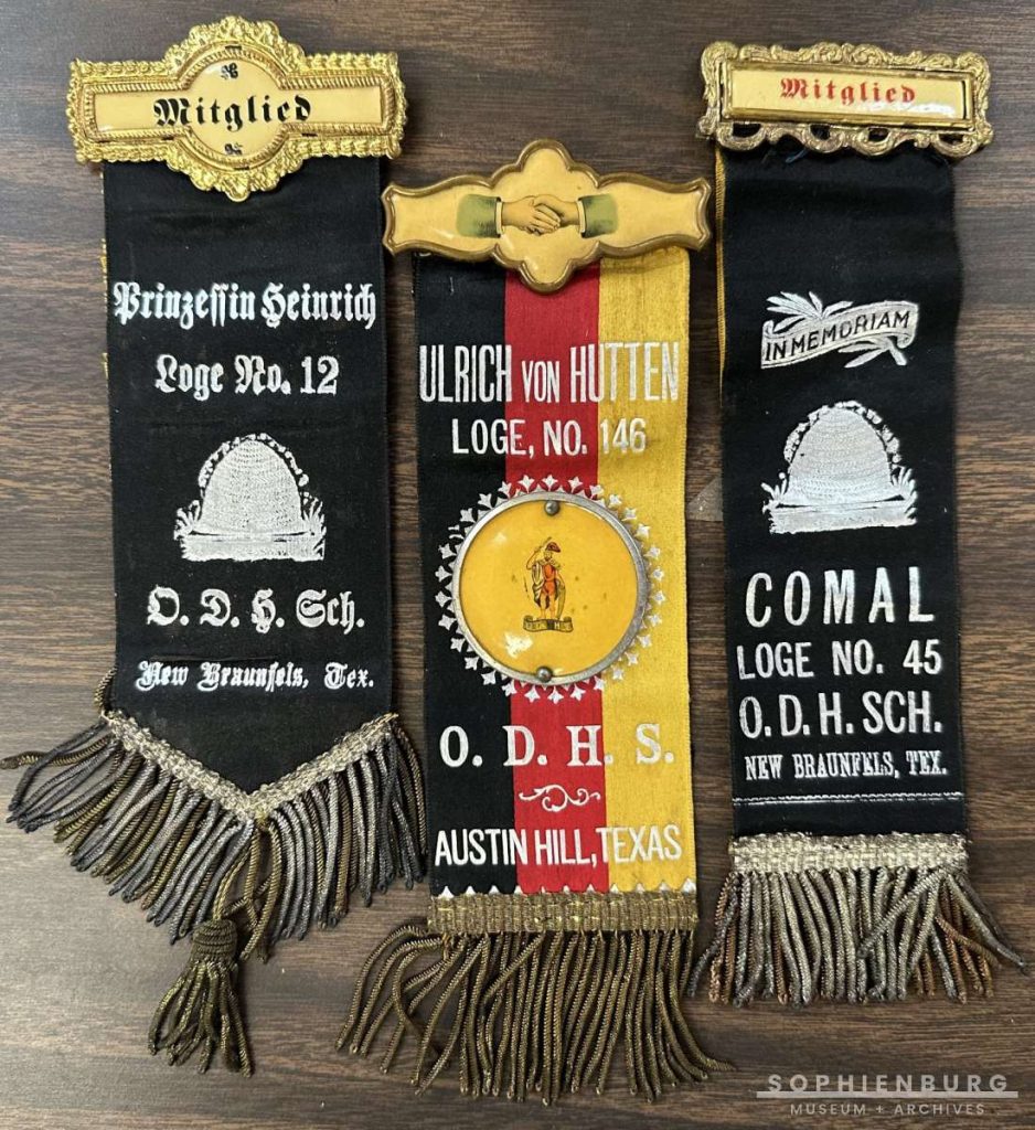 PHOTO CAPTION: Hermann Sons Lodge members wore pins/ribbons denoting their lodge name. On the back side of the ribbon, there was a black ribbon to wear for mourning the death of a member. L-R: Prinzessen Heinrich Sister Lodge mourning ribbon. O.D.H.Sch Ordern der Hermann Schwester (sister); Ullrich von Hutten, O.D.H.S. Austin Hill (Kohlenberg Road); Comal O.D.H.Sch. Sister Lodge, which is one that merged with Teutonia to make New Braunfels Hermann Sons.